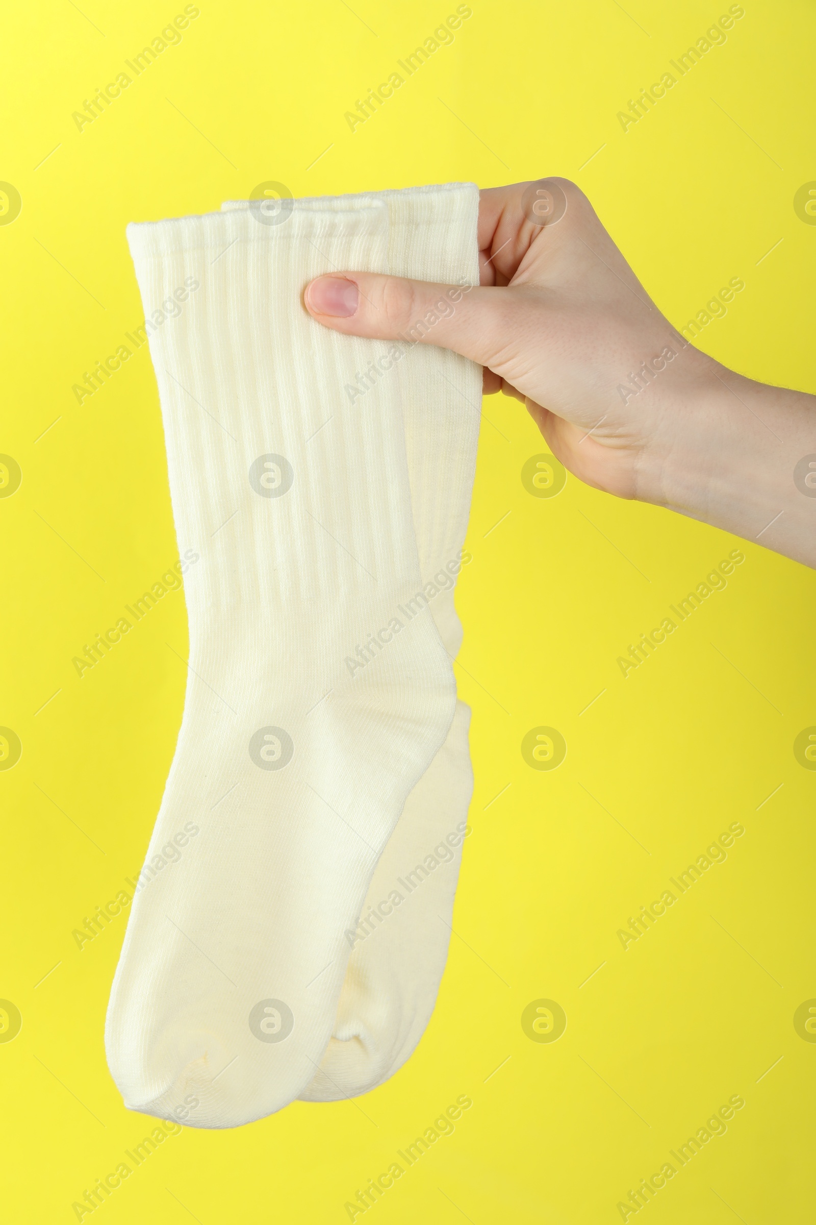 Woman with pair of socks on yellow background, closeup Photo of Woman with pair of socks on yellow background, closeup