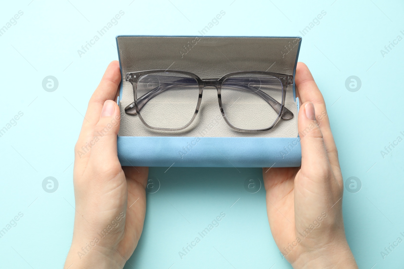Woman with glasses in case on light blue background, top view Photo of Woman with glasses in case on light blue background, top view