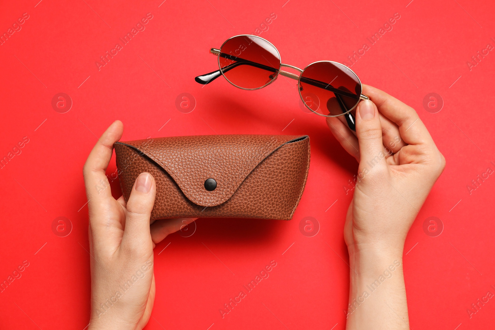 Woman with sunglasses and case on red background, top view Photo of Woman with sunglasses and case on red background, top view