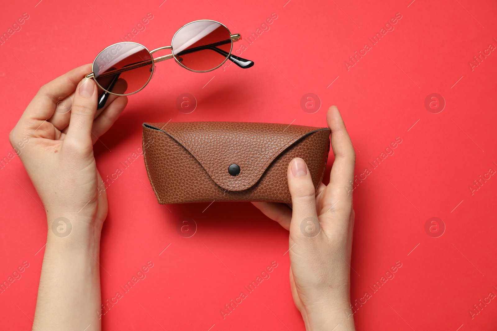 Woman with sunglasses and case on red background, top view Photo of Woman with sunglasses and case on red background, top view