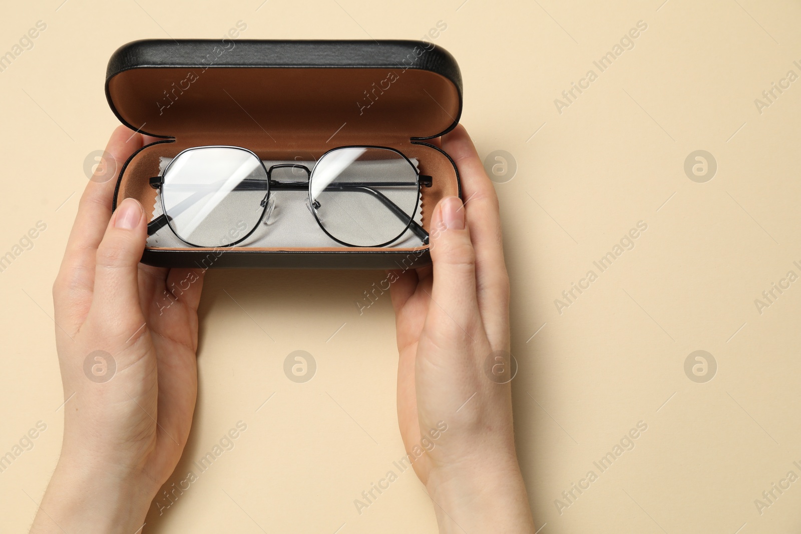 Woman with glasses in case on beige background, top view Photo of Woman with glasses in case on beige background, top view