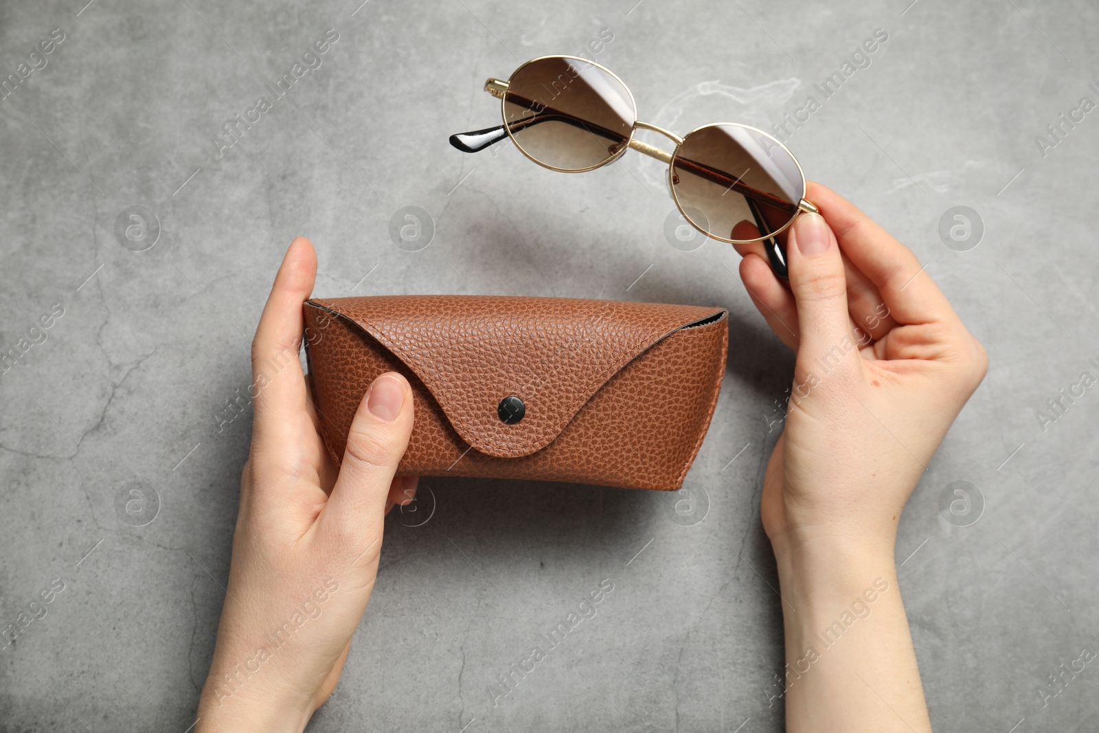 Woman with sunglasses and case on grey background, top view Photo of Woman with sunglasses and case on grey background, top view