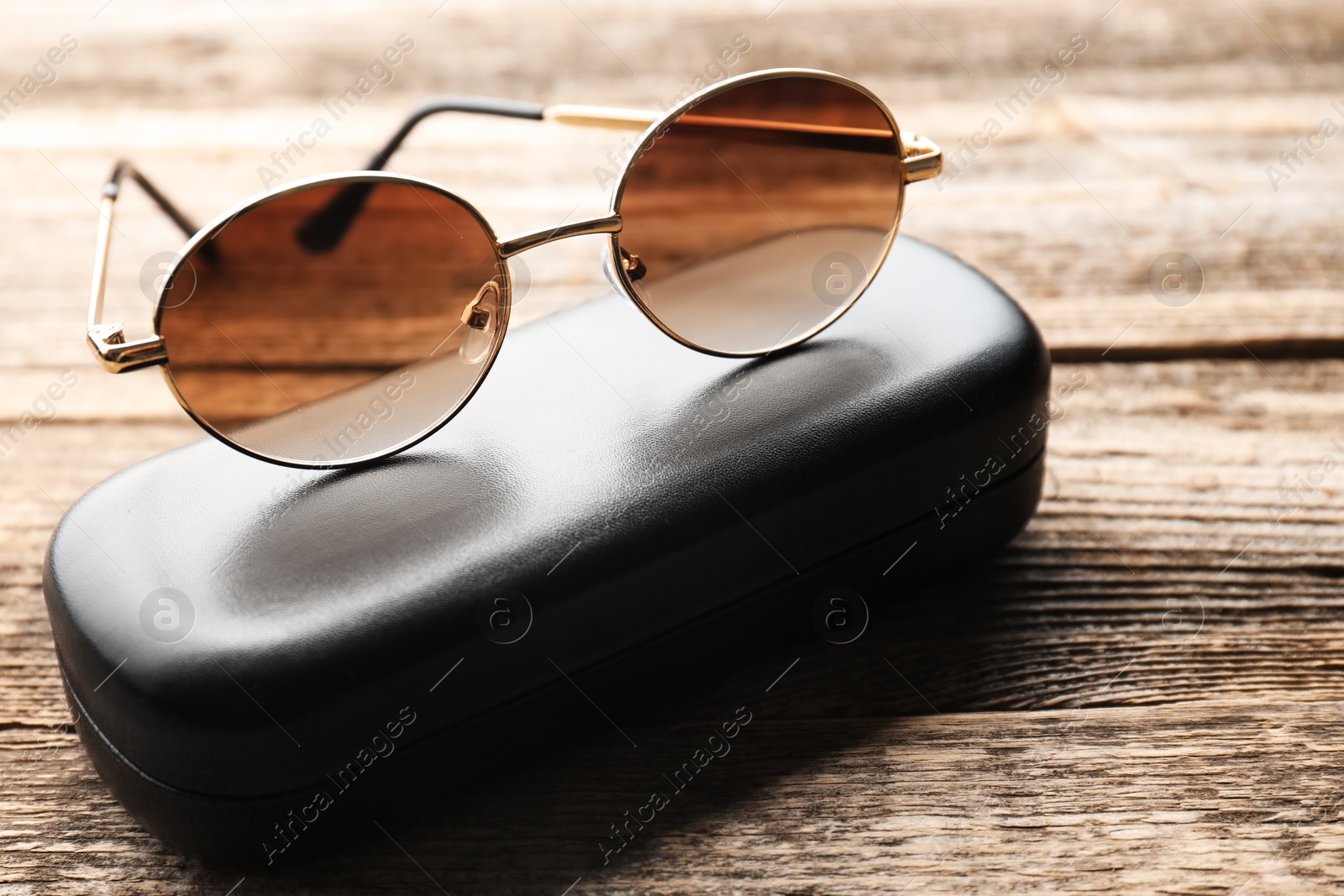 Stylish sunglasses and case on wooden table, closeup Photo of Stylish sunglasses and case on wooden table, closeup