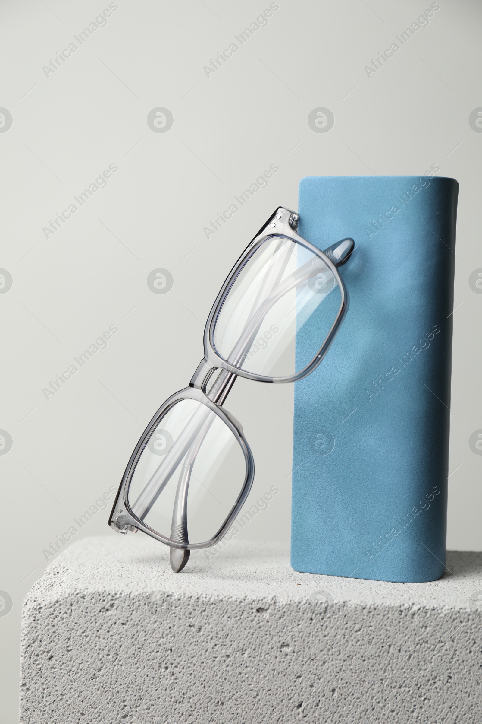Stylish glasses and case on stone surface against light grey background Photo of Stylish glasses and case on stone surface against light grey background