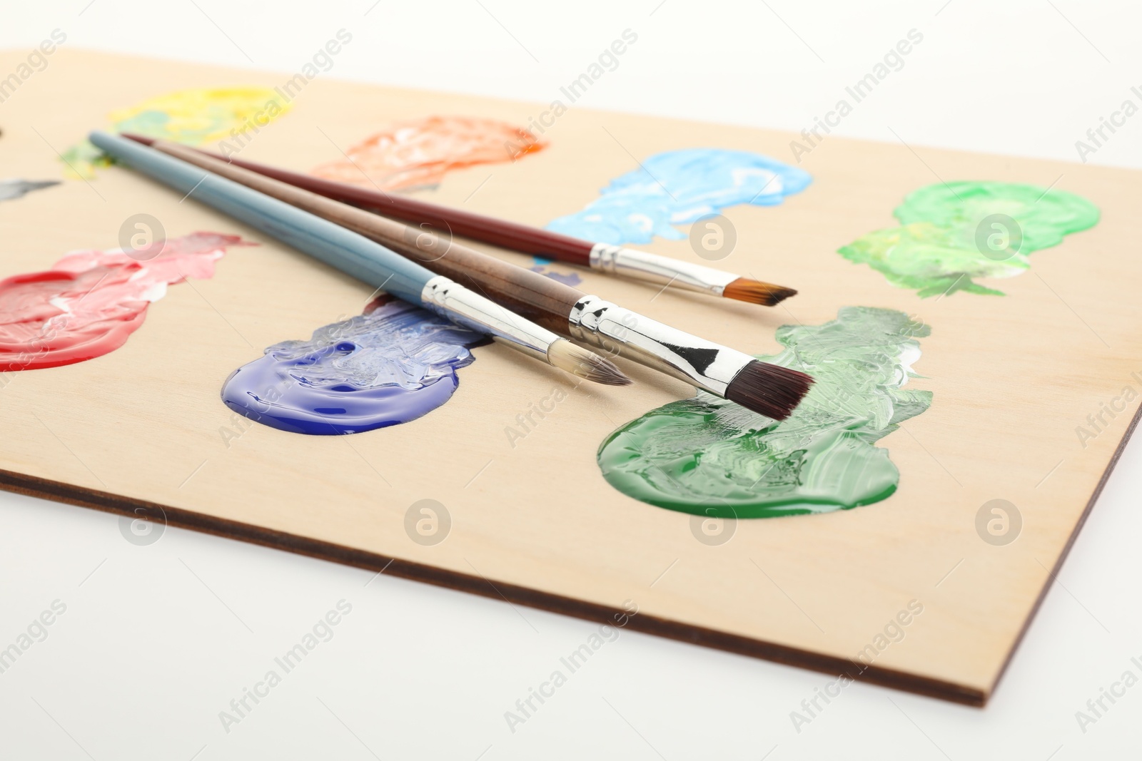 Wooden palette with paints and brushes on white background, closeup Photo of Wooden palette with paints and brushes on white background, closeup
