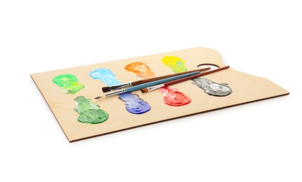 Photo of Wooden palette with paints and brushes isolated on white