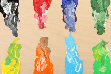 Photo of Wooden palette with paints as background, top view