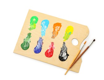 Photo of Wooden palette with paints and brushes isolated on white, top view