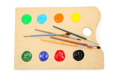Photo of Wooden palette with paints and brushes isolated on white, top view