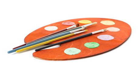 Photo of Wooden palette with paints and brushes isolated on white