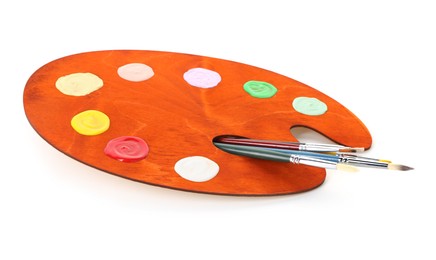 Photo of Wooden palette with paints and brushes isolated on white