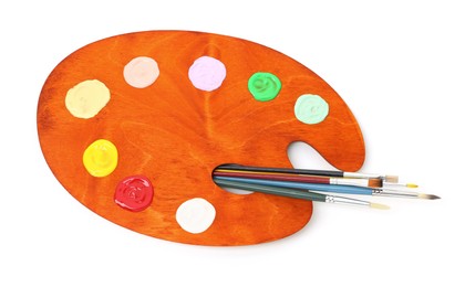 Photo of Wooden palette with paints and brushes isolated on white, top view