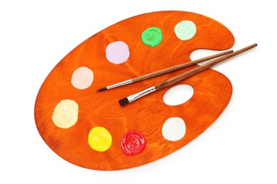 Photo of Wooden palette with paints and brushes isolated on white, top view