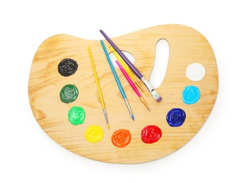Photo of Wooden palette with paints and brushes isolated on white, top view