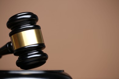 Photo of Judge's gavel and sound block on pale brown background, closeup. Space for text