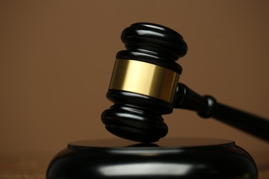 Photo of Judge's gavel and sound block on brown background, closeup