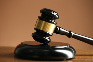 Photo of Judge's gavel and sound block on wooden table against pale brown background, closeup