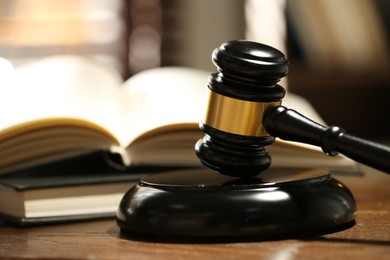 Photo of Judge's gavel, sound block and books on wooden table against blurred background, closeup