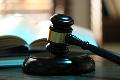 Photo of Judge's gavel, sound block and books on wooden table against blurred background, closeup