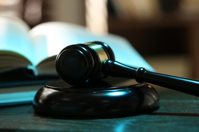 Photo of Judge's gavel, sound block and books on wooden table against blurred background, closeup