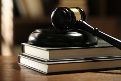 Photo of Judge's gavel, sound block and books on wooden table against blurred background, closeup