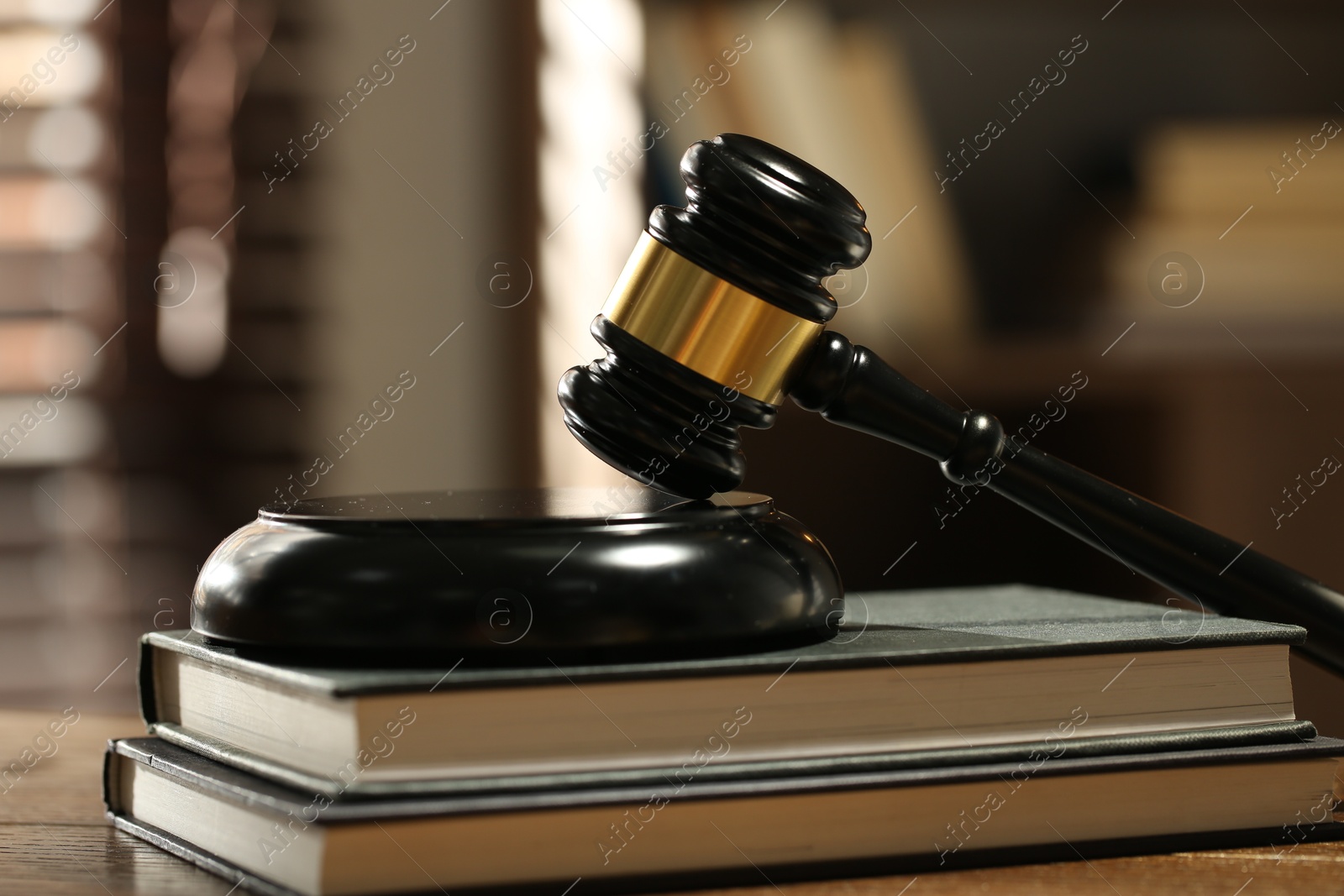 Judge's gavel, sound block and books on wooden table against blurred background, closeup Photo of Judge's gavel, sound block and books on wooden table against blurred background, closeup