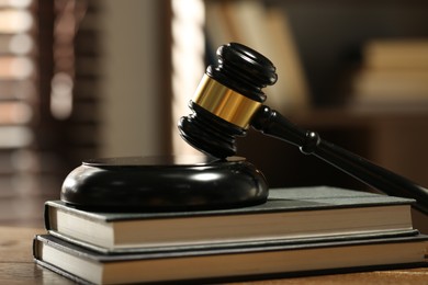 Photo of Judge's gavel, sound block and books on wooden table against blurred background, closeup