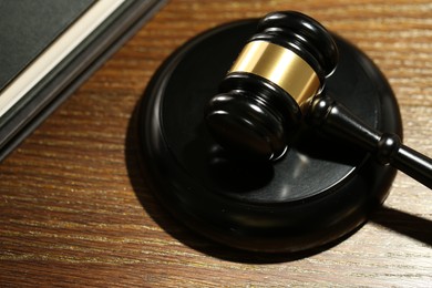 Photo of Judge's gavel, sound block and books on wooden table, closeup