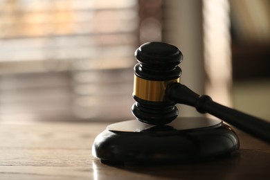 Photo of Judge's gavel and sound block on wooden table against blurred background, closeup. Space for text
