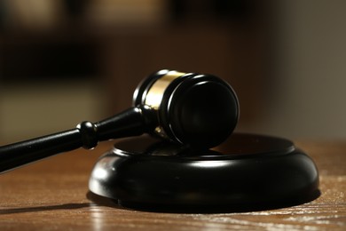 Photo of Judge's gavel and sound block on wooden table against blurred background, closeup