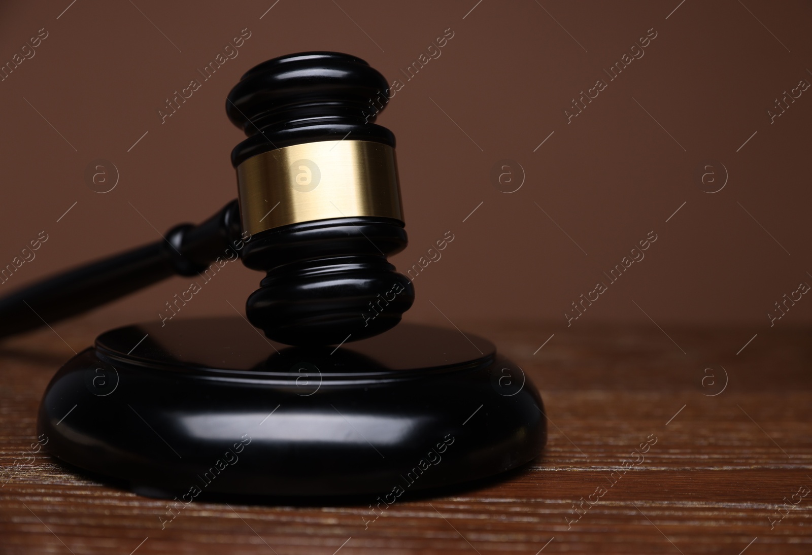 Judge's gavel and sound block on wooden table against brown background, closeup. Space for text Photo of Judge's gavel and sound block on wooden table against brown background, closeup. Space for text