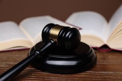 Photo of Judge's gavel, sound block and books on wooden table, closeup