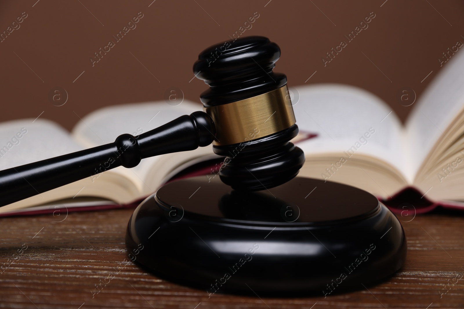 Judge's gavel, sound block and books on wooden table against brown background, closeup Photo of Judge's gavel, sound block and books on wooden table against brown background, closeup