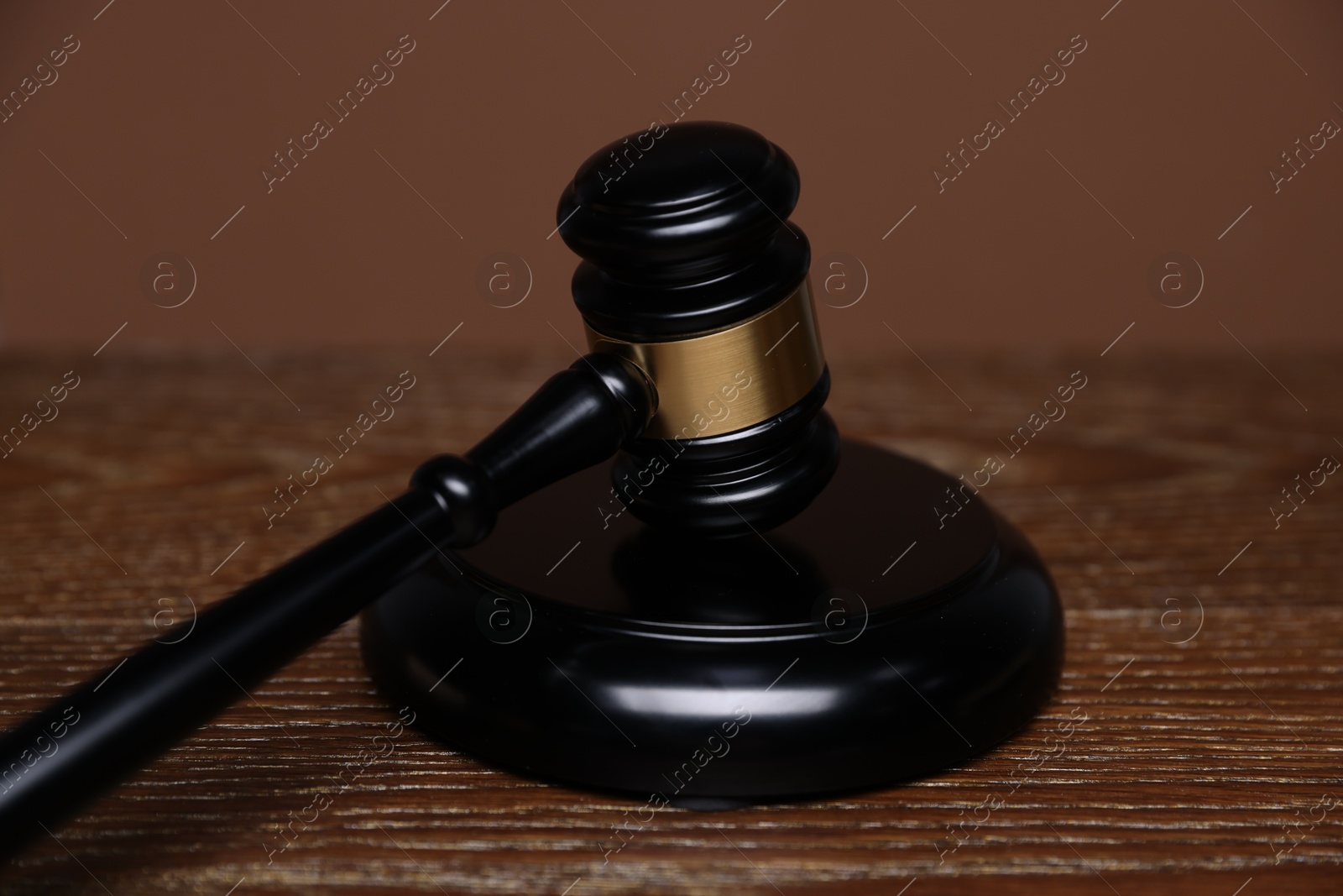 Judge's gavel and sound block on wooden table against brown background, closeup Photo of Judge's gavel and sound block on wooden table against brown background, closeup