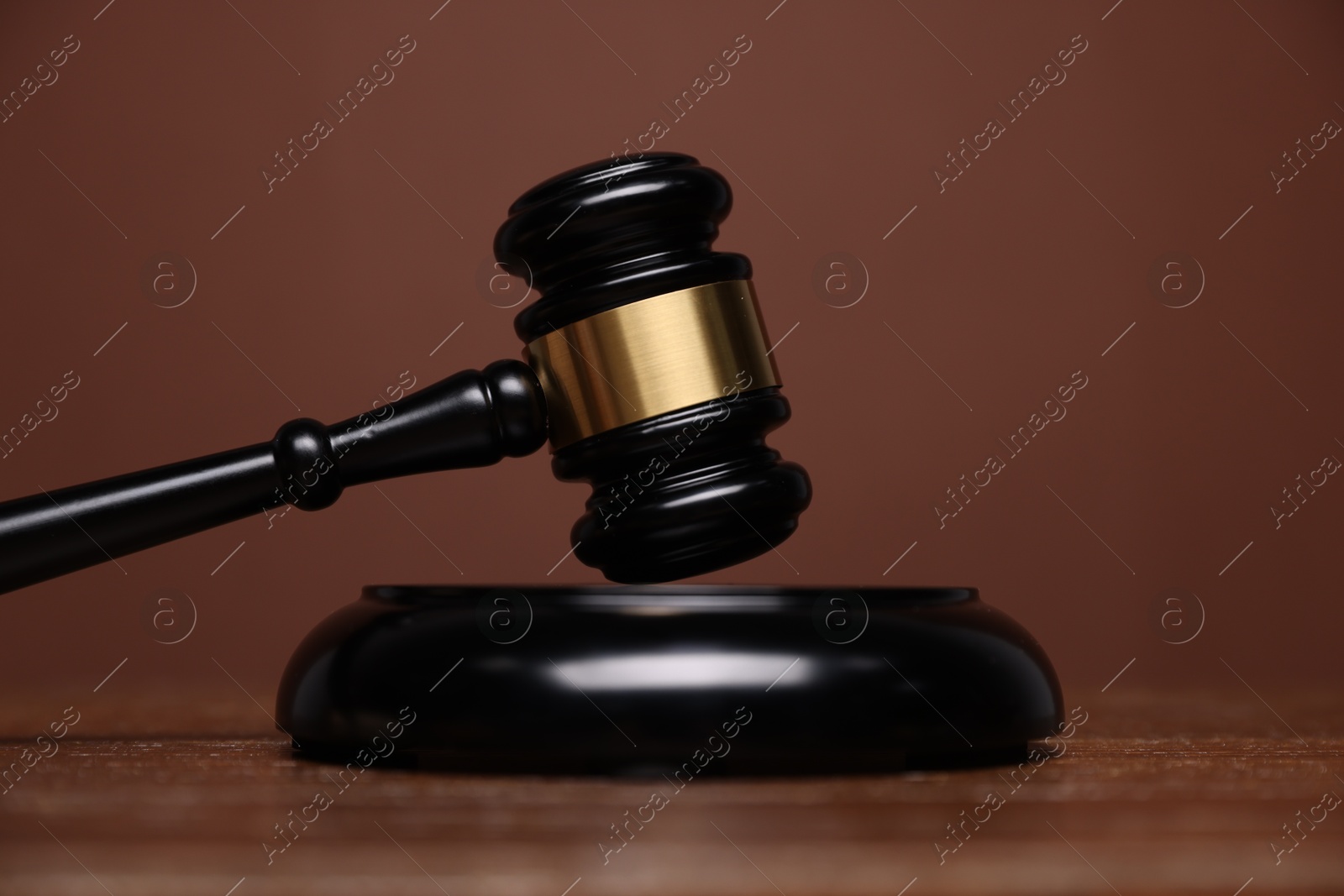 Judge's gavel and sound block on wooden table against brown background, closeup Photo of Judge's gavel and sound block on wooden table against brown background, closeup