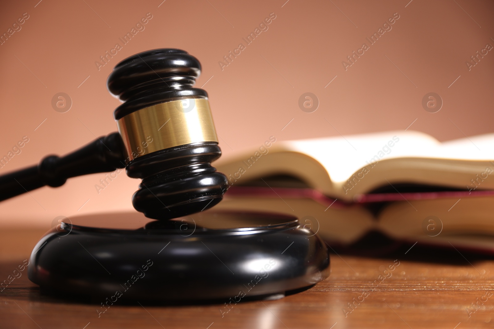 Judge's gavel, sound block and books on wooden table against pale brown background, closeup Photo of Judge's gavel, sound block and books on wooden table against pale brown background, closeup