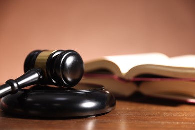 Photo of Judge's gavel, sound block and books on wooden table against pale brown background, closeup