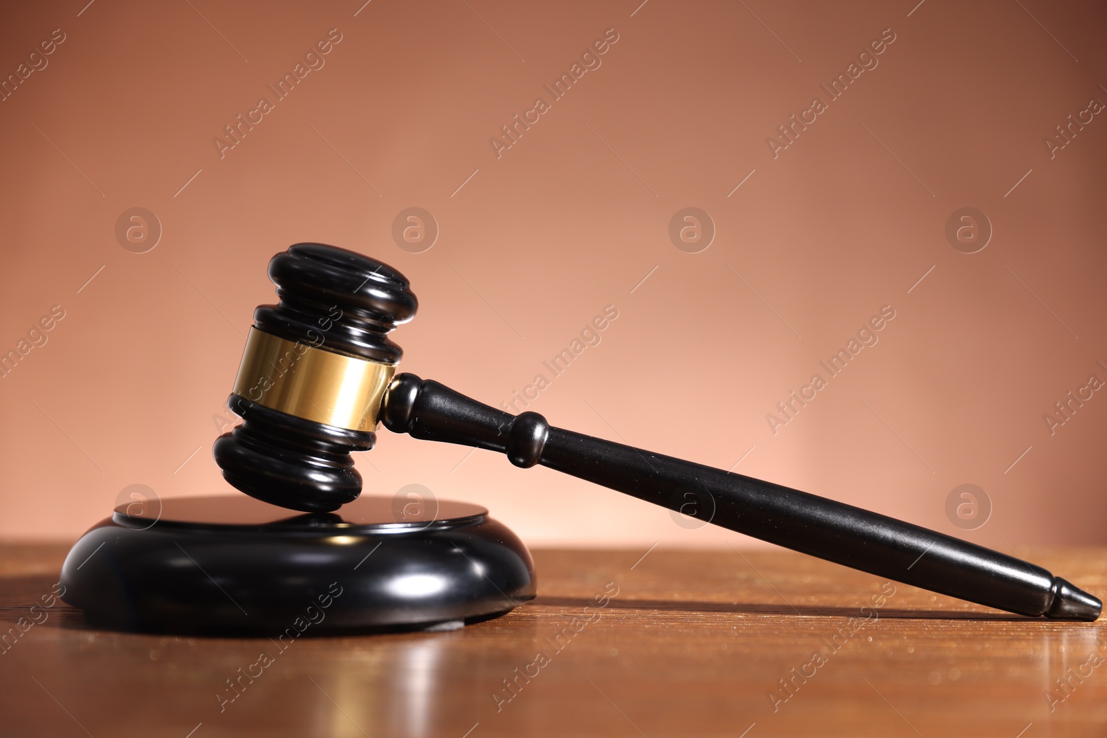Judge's gavel and sound block on wooden table against pale brown background Photo of Judge's gavel and sound block on wooden table against pale brown background