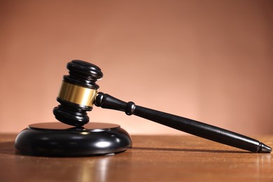 Photo of Judge's gavel and sound block on wooden table against pale brown background