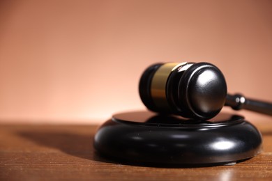 Photo of Judge's gavel and sound block on wooden table against pale brown background, closeup. Space for text