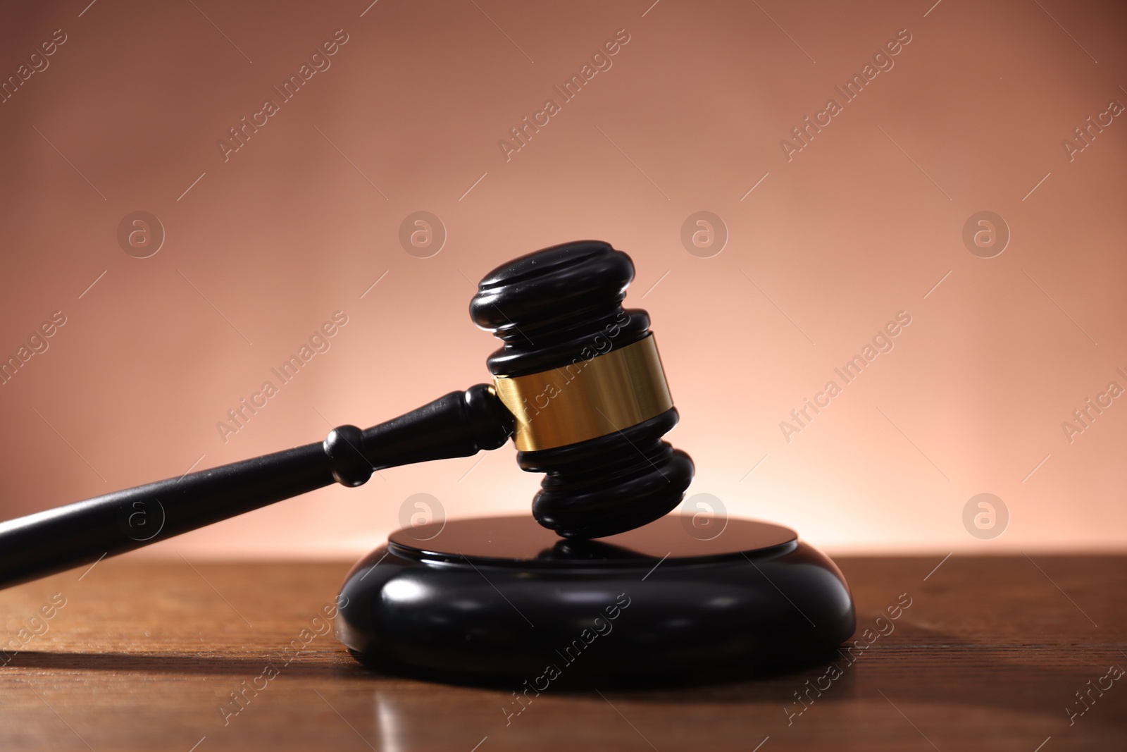 Judge's gavel and sound block on wooden table against pale brown background Photo of Judge's gavel and sound block on wooden table against pale brown background