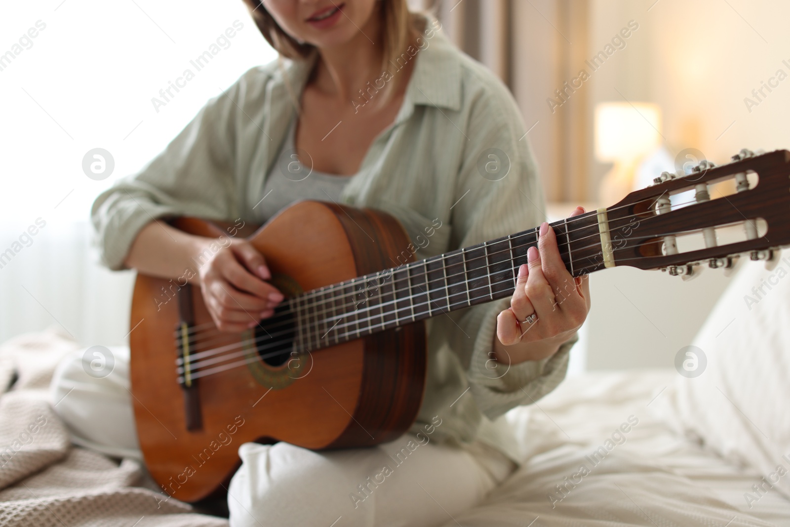 Young woman playing guitar at home, closeup Photo of Young woman playing guitar at home, closeup