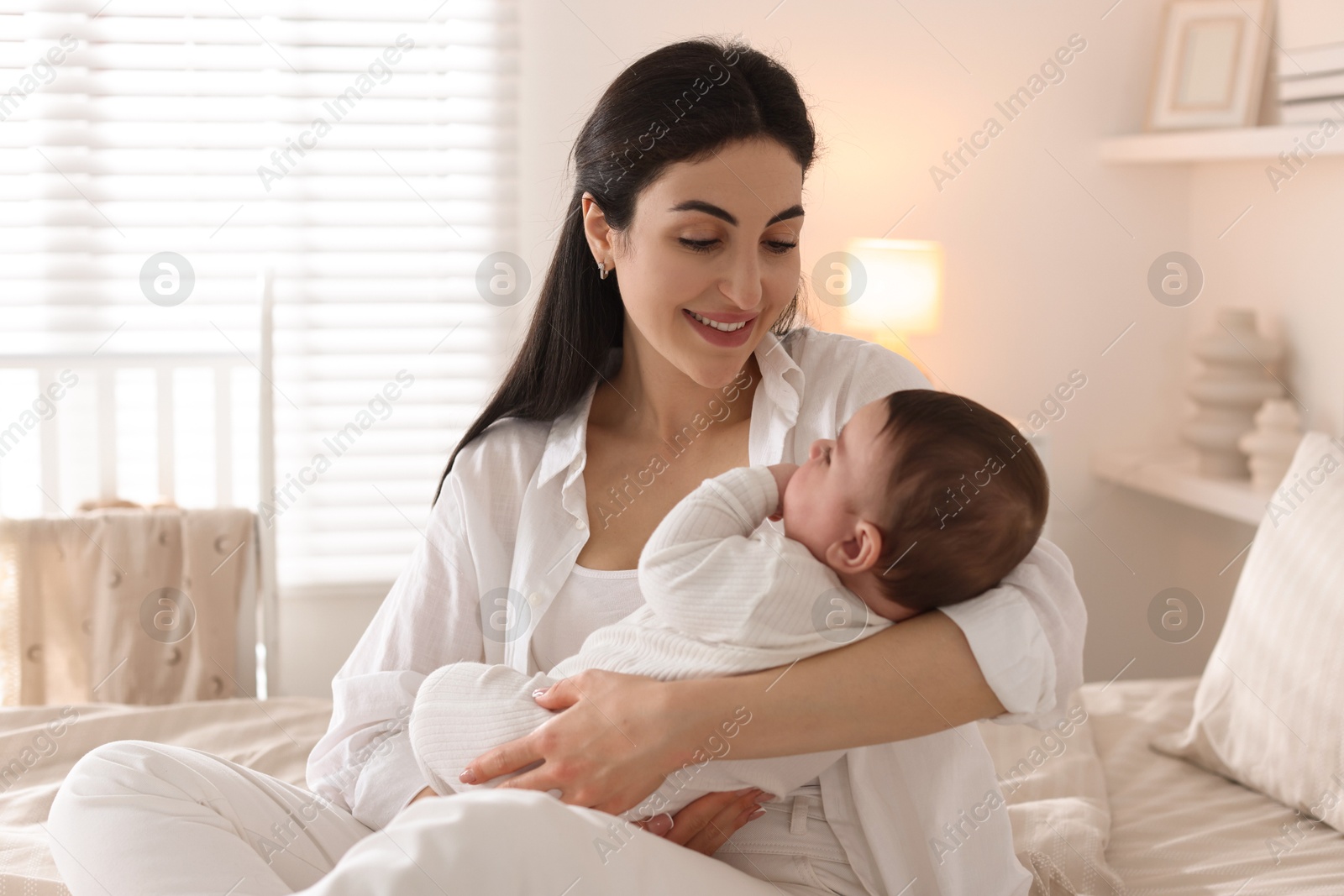 Bedtime. Mother with her cute little baby on bed at home Photo of Bedtime. Mother with her cute little baby on bed at home