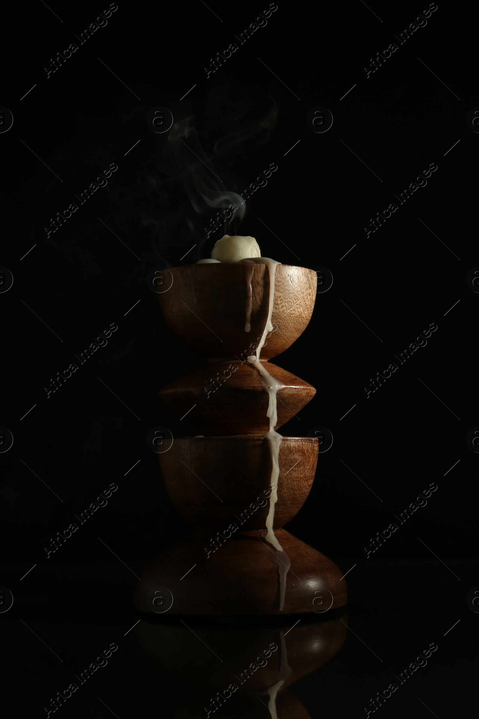 Extinguished candle in candlestick on mirror surface against black background Photo of Extinguished candle in candlestick on mirror surface against black background