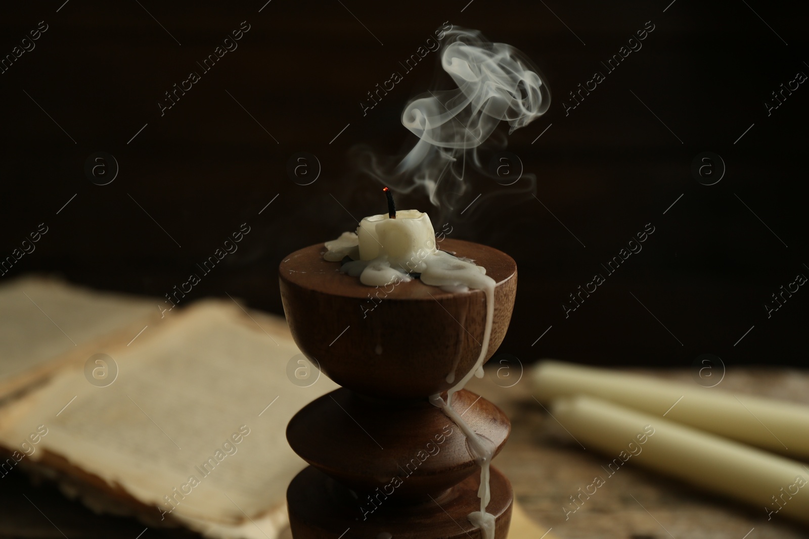 Smoldering candle in candlestick on table, closeup Photo of Smoldering candle in candlestick on table, closeup
