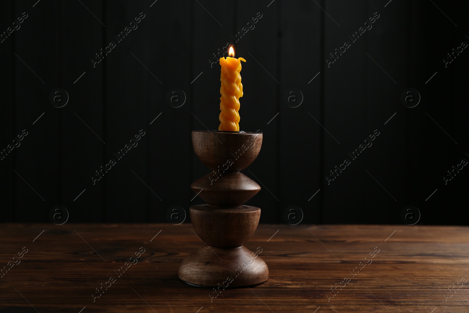 Burning candle in candlestick on wooden table Photo of Burning candle in candlestick on wooden table