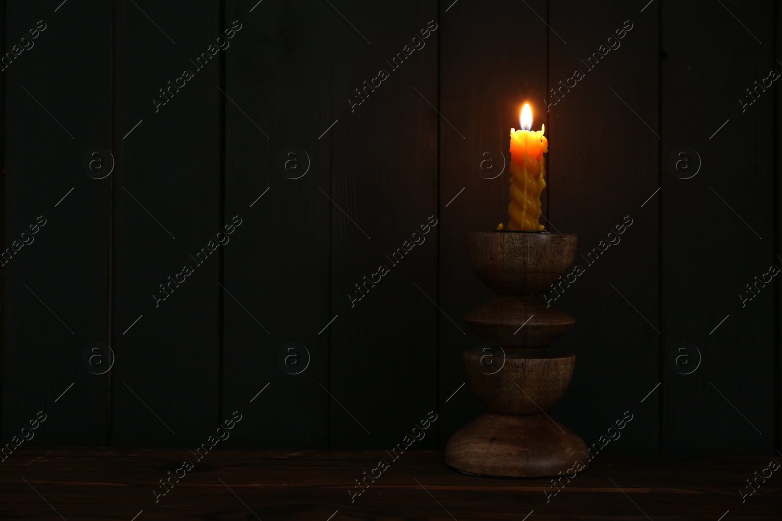 Burning candle in candlestick on wooden table Photo of Burning candle in candlestick on wooden table