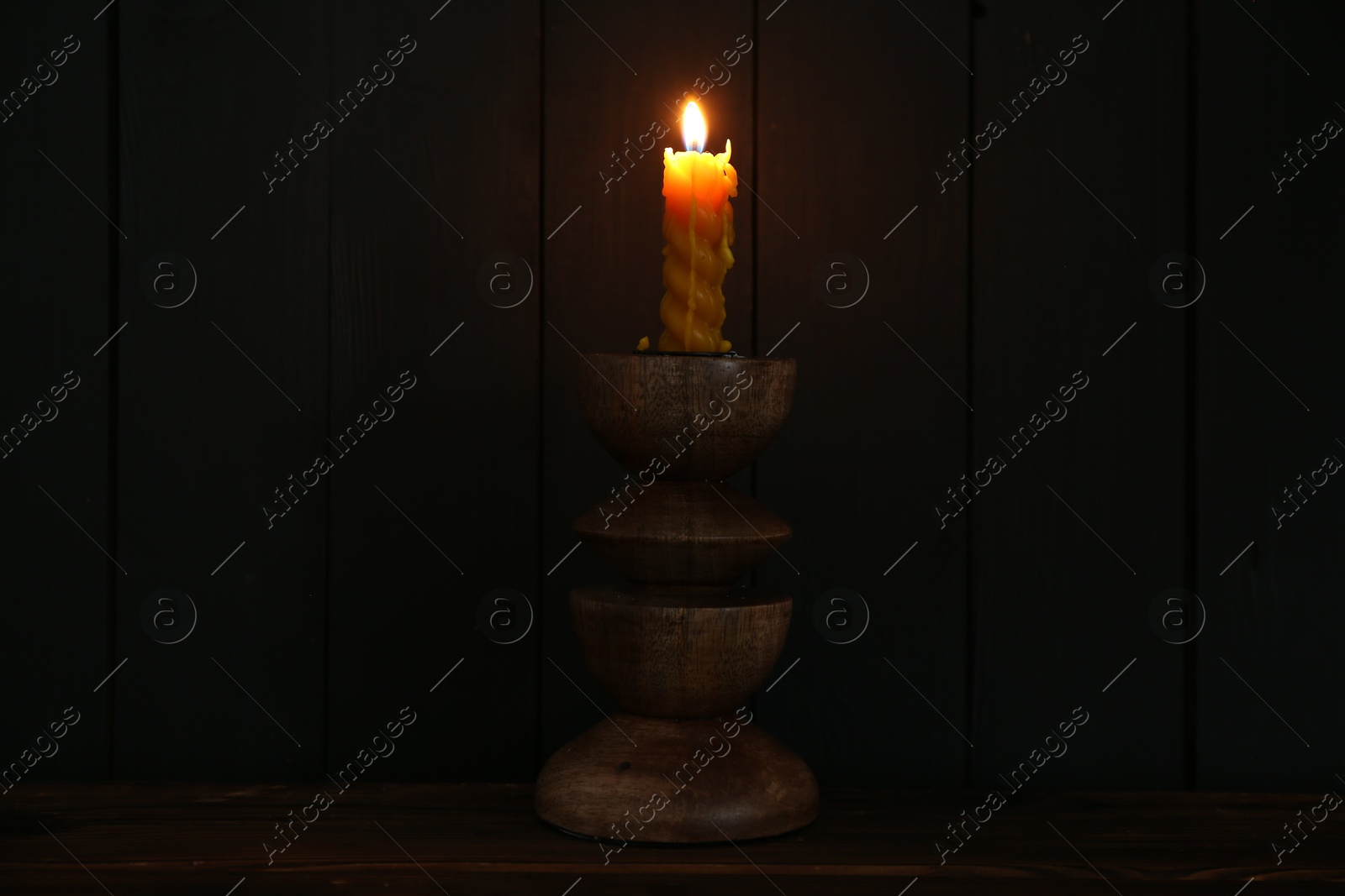 Burning candle in candlestick on wooden table Photo of Burning candle in candlestick on wooden table