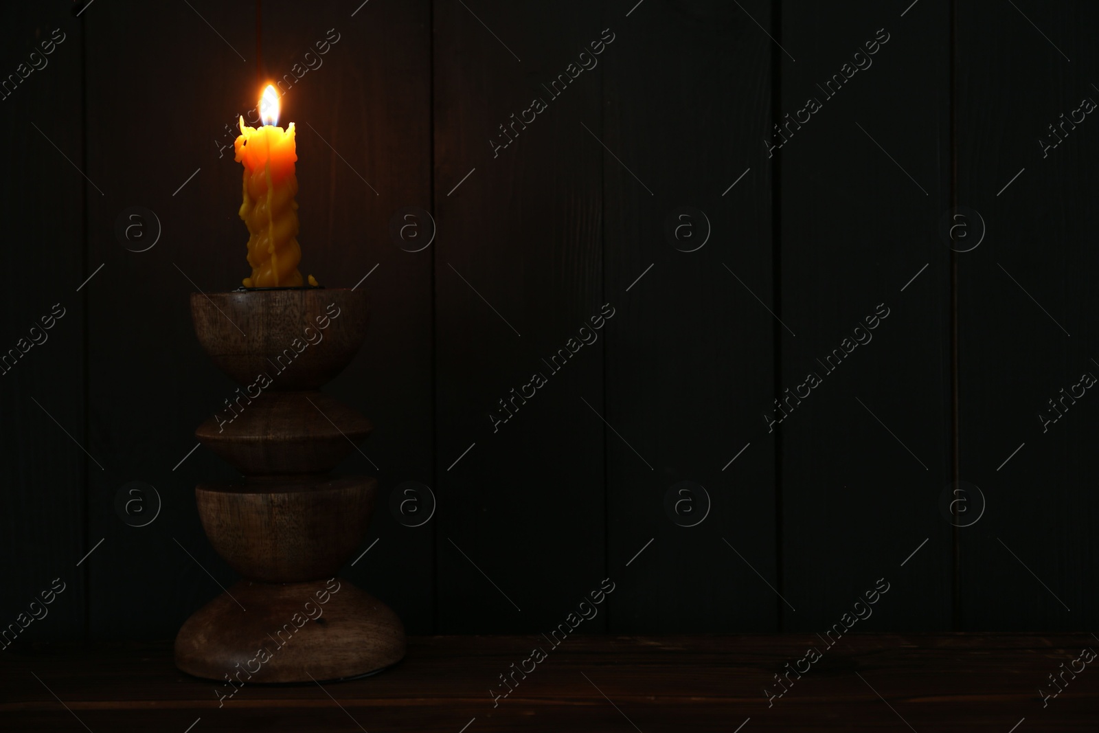 Burning candle in candlestick on wooden table Photo of Burning candle in candlestick on wooden table