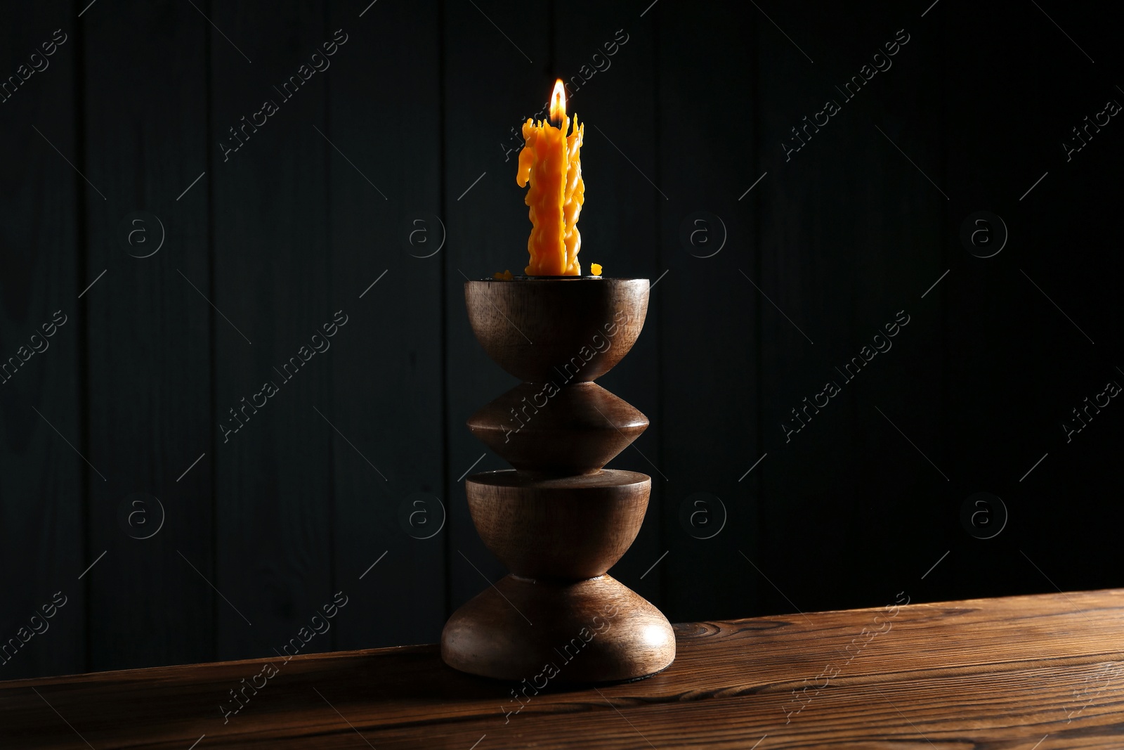 Burning candle in candlestick on wooden table Photo of Burning candle in candlestick on wooden table